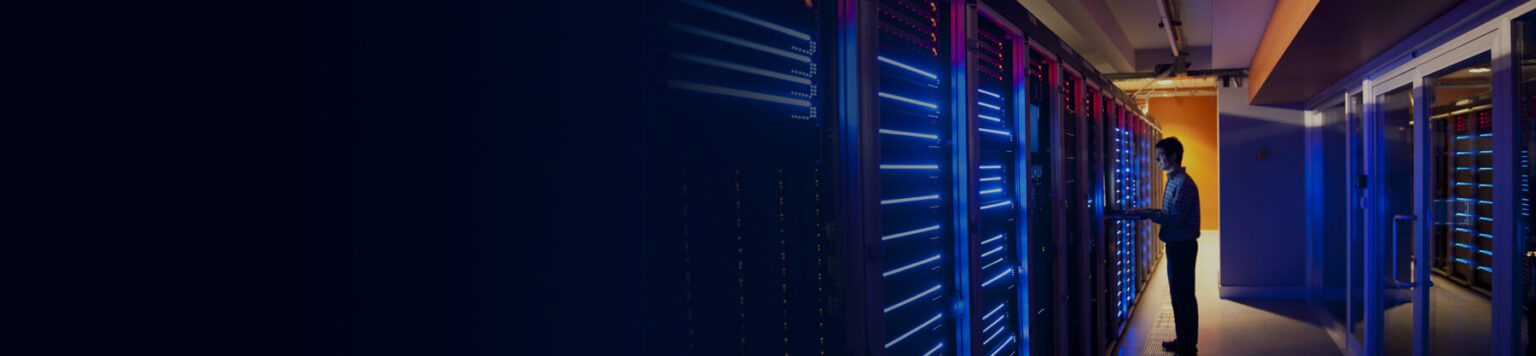 Male technician standing in front of glowing servers in a datacente