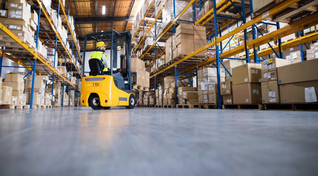 Man in yellow hard hat and high-visual top operating factory forklift