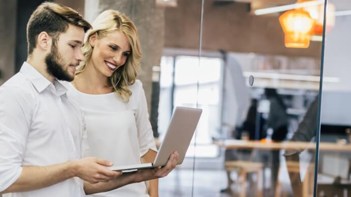 Male and female coworkers looking at laptop in business office