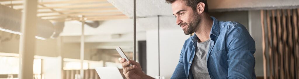 Casually dressed man, showing wireless connectivity by using his laptop and phone at the same time.