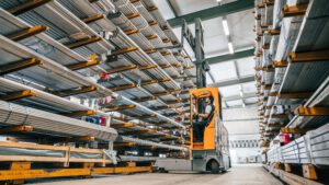 Inside a steel warehouse with a man driving a forklift