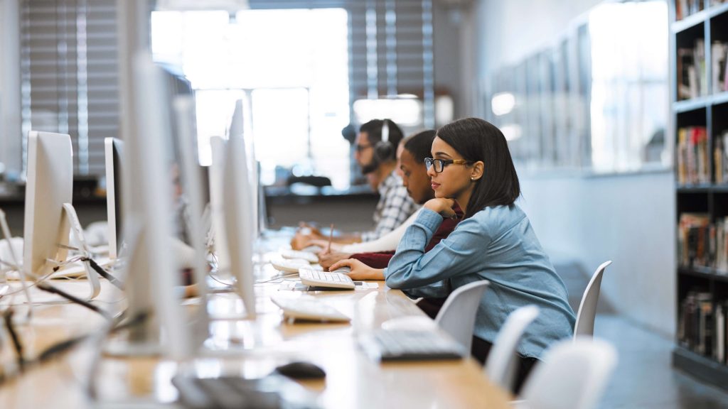 3 people on a computer in a university library