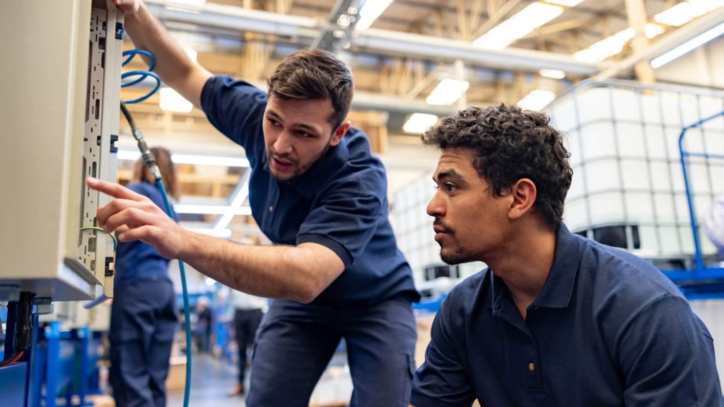 Two workers on a circuit board in a factory