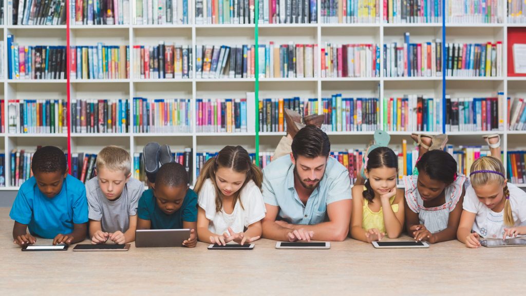 A lin of children lying on the floor using electronic devices