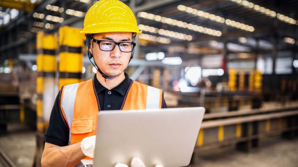 Factory worker wearing safety gear on a laptop